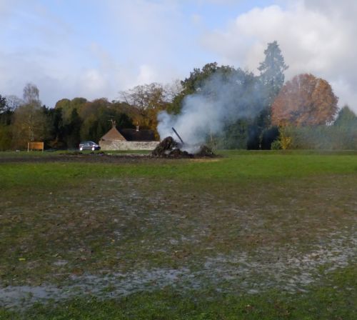 Smoldering remains of bonfire on village green next day